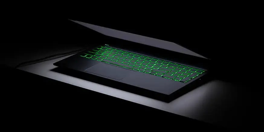 A laptop half open with a green backlit keyboard