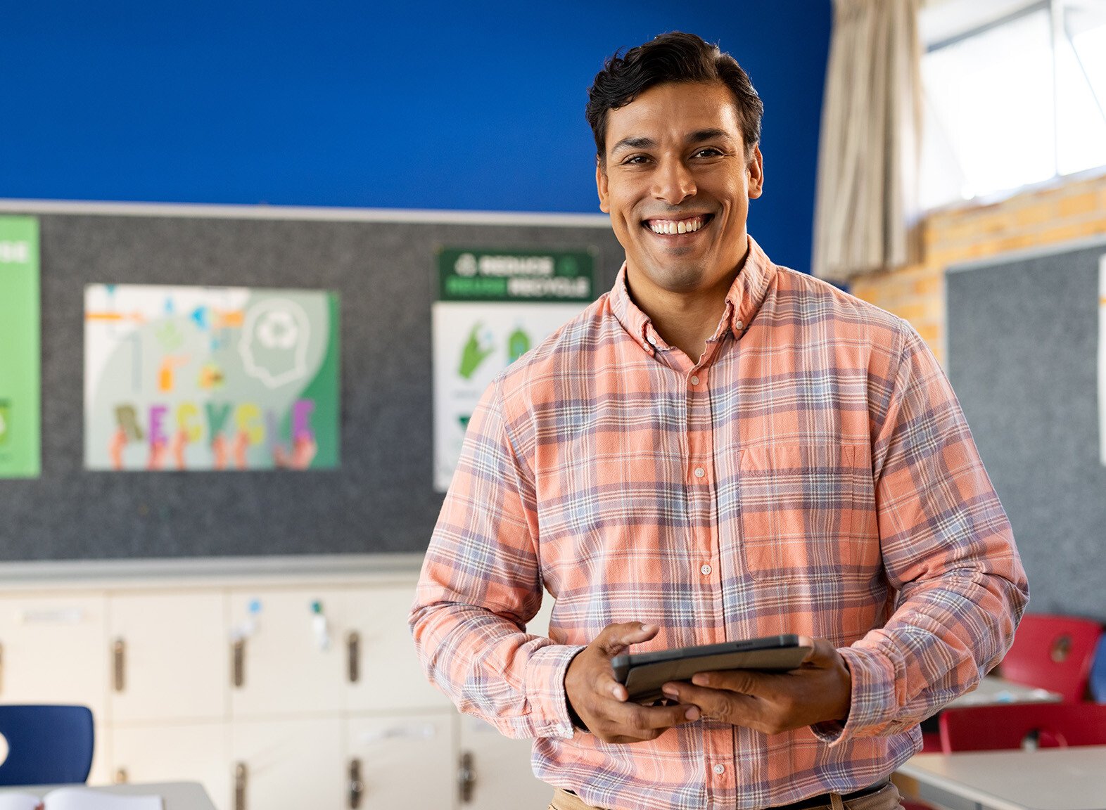 Happy male primary school teacher stood in a classroom