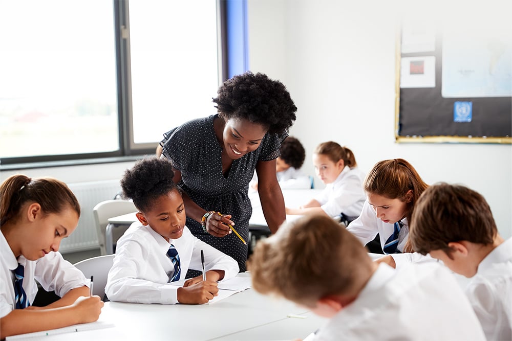 A teacher in an International school supporting pupils doing group work in class