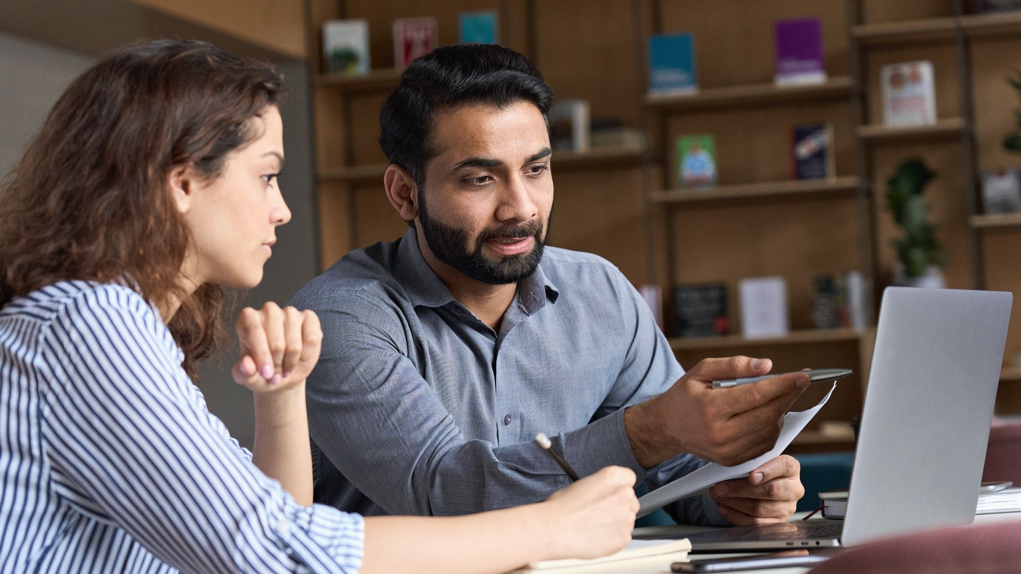 A learner and a lecturer in a further education setting working at a laptop 