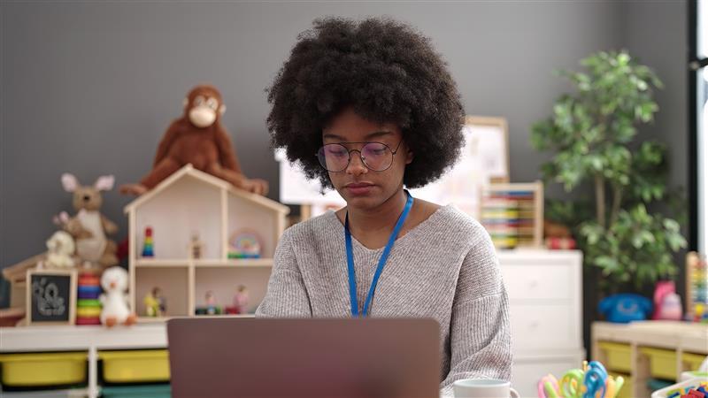 Teacher sat down in classroom on her laptop