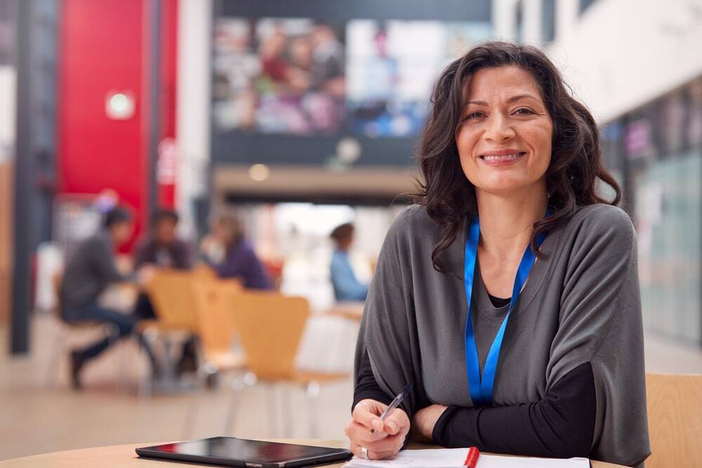 female school staff member sat smiling in the school hall