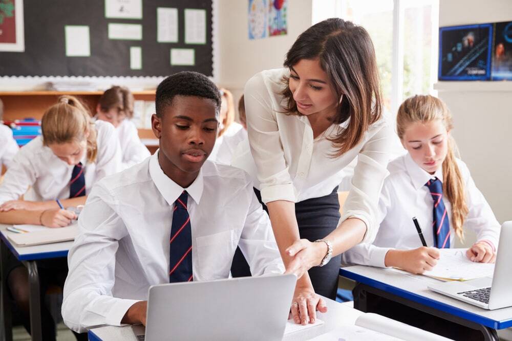 female teacher helping male student in class